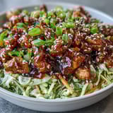 Tasty ground chicken simmers with crisp cabbage and carrots in a savory sauce, garnished with green onions and sesame seeds.