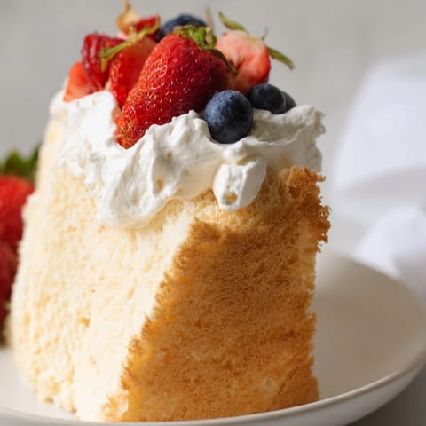 Fluffy angel food cake, perfectly golden, ready to be sliced and served with whipped cream.
