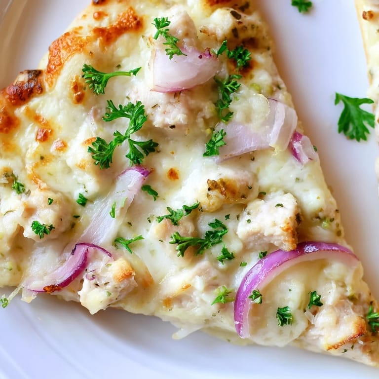 Savory diced chicken and melted mozzarella top a crisp, golden-brown crust of the Chicken Alfredo Pizza, ready to slice.