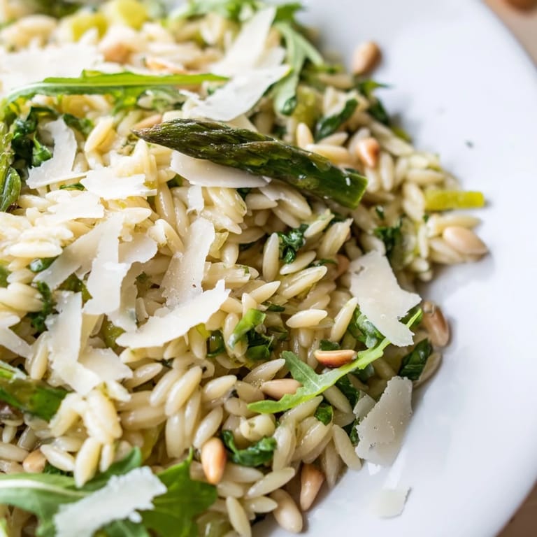 This chilled Asparagus Lemon Orzo Salad features bright green ribbons and fluffy pasta, garnished with fresh herbs and a sprinkle of Parmesan.  
