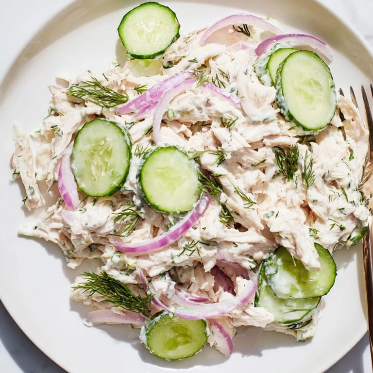Creamy cucumber chicken salad served in a white bowl, garnished with green onions and dill for a refreshing light lunch.