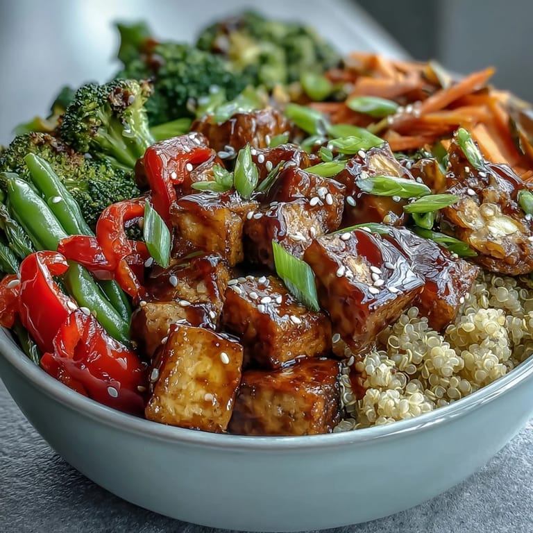Close-up of a hearty vegan bowl featuring fluffy quinoa, crisp broccoli, bell peppers, and drizzled savory teriyaki sauce.