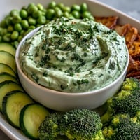 Fresh green snack board with cucumber, snap peas, and avocado ranch dip, perfect for healthy gatherings.
