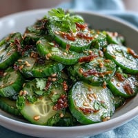 Crisp Asian cucumber salad with sesame and rice vinegar, tossed with green onions and fresh cilantro for a tangy, refreshing side dish.