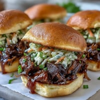 1. Juicy, smoky BBQ baby shower brisket sliders piled high on soft slider buns with tangy slaw and pickles.  